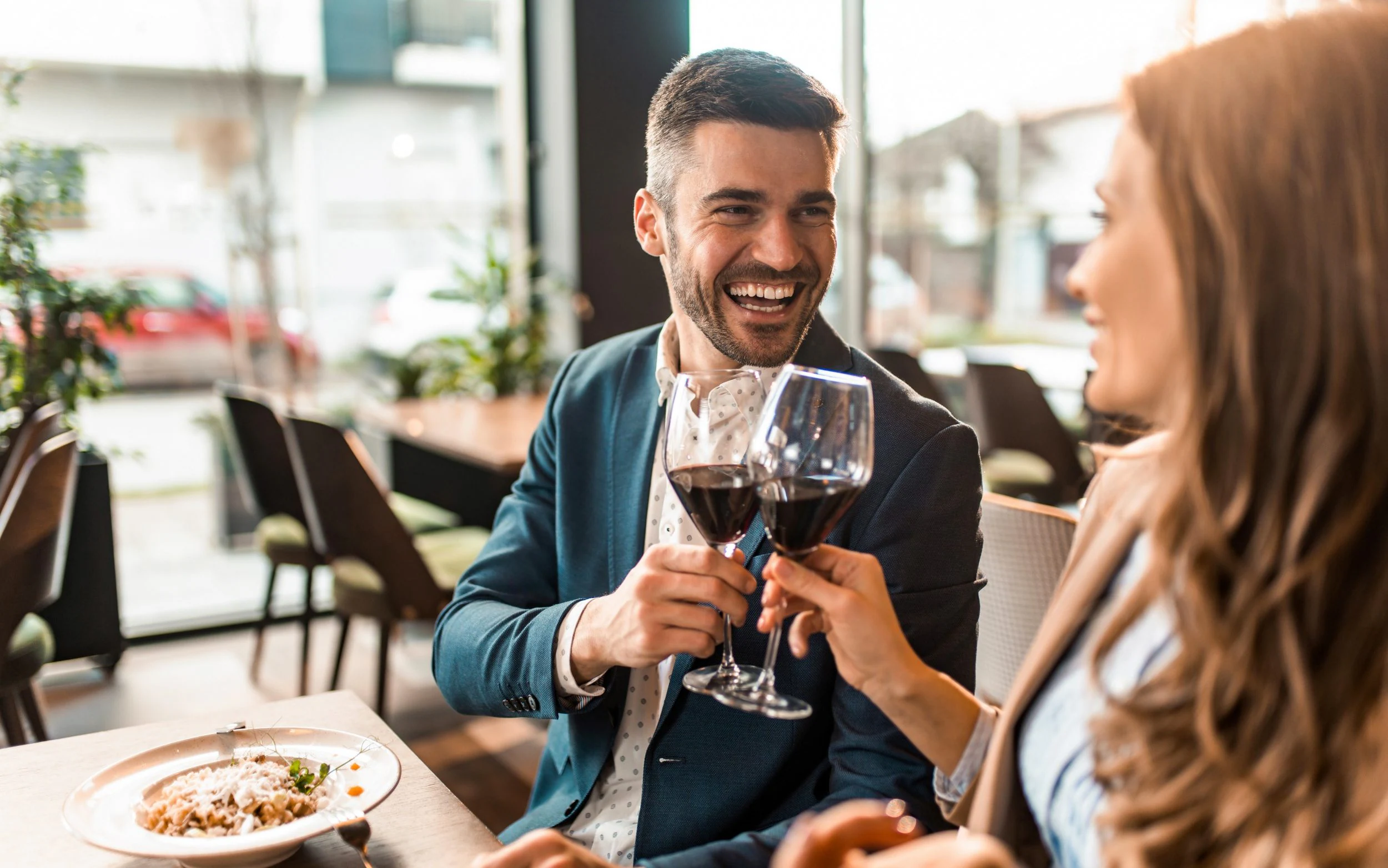 A couple at a restaurant cheering to glasses of wine
