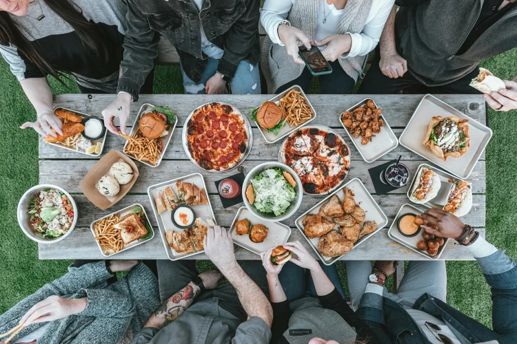 Picnic table with delicious food and people eating