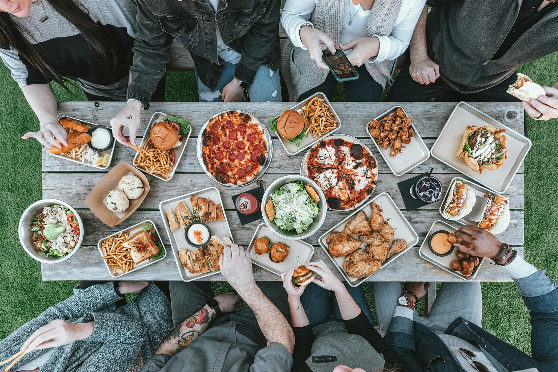 Picnic table with delicious food and people eating